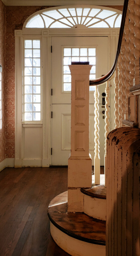 The entry way to our home with a Georgian style front door and an antique staircase with barley twist spindles.